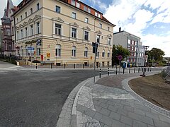 Blick auf eine Kreuzung mit einem gelben Gebäude im Hintergund.