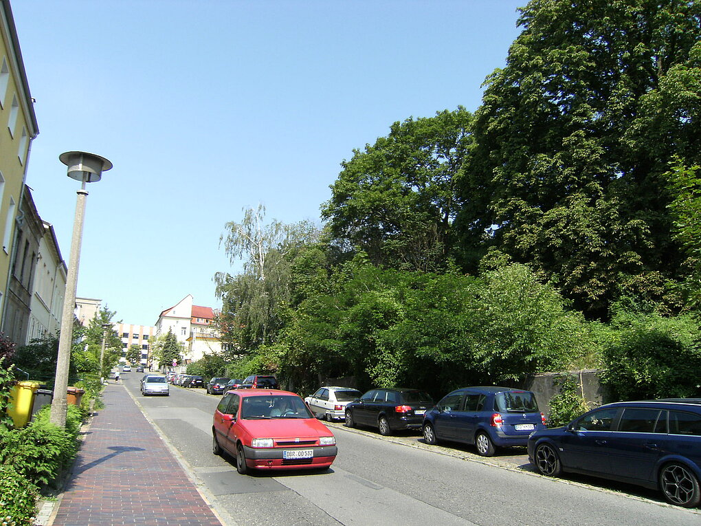 Blick auf eine Straße mit fahrenden und parkenden Autos.