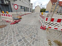 Sanierte gepflasterte Straße mit Absperrung.