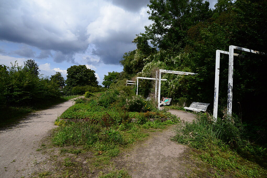Grüne Landschaft mit zwei sitzenden Personen auf einer Parkbank.