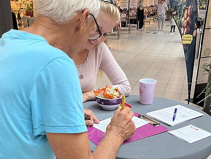 Älterer Herr lässt sich Fragebogen am RGS-Stand erklären.