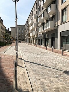 Sanierte Straße und Gehwege mit Baufahrzeugen im Hintergrund.