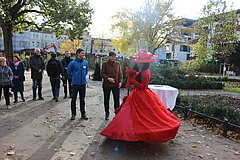 Menschen beobachten eine Frau in einem roten Kleid, die auf einer Straße tanzt