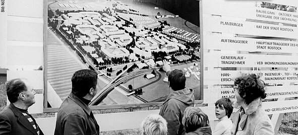 Menschen betrachten eine große Karte von Rostock-Dierkow an einer Wand