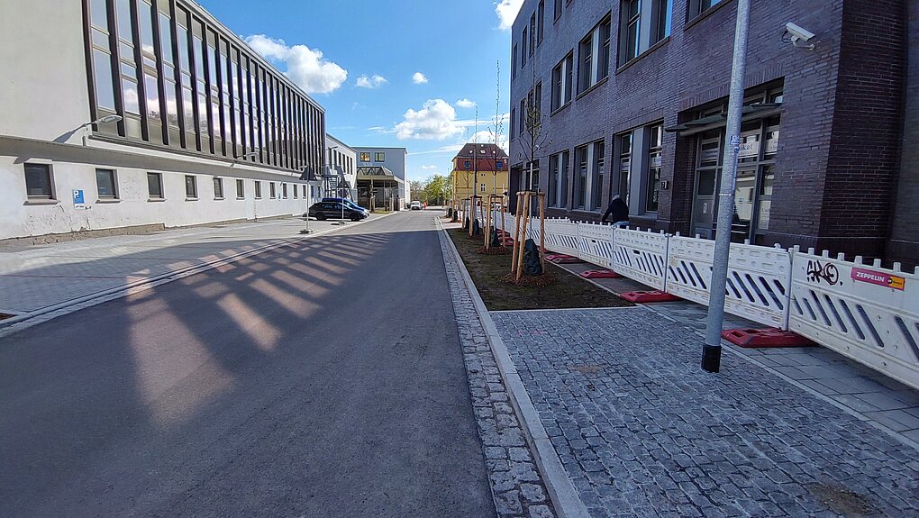 Breite Straße mit Gebäuden auf beiden Seiten und einem blauen Himmel