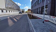 Breite Straße mit Gebäuden auf beiden Seiten und einem blauen Himmel