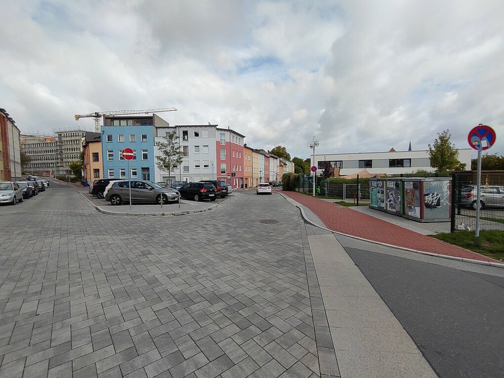 Blick auf eine Abzweigung mit parkenden Autos.