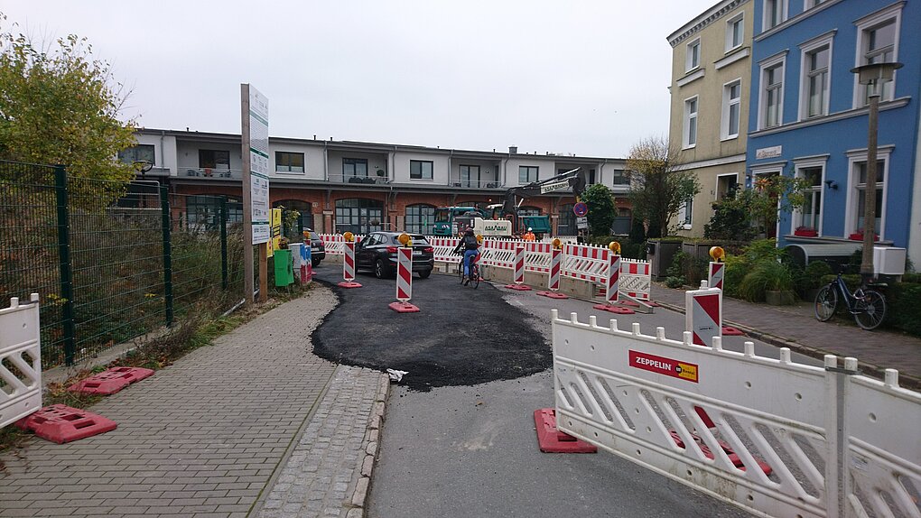Blick auf eine Baustelle mit fahrenden Autos und einer Radfahrerin
