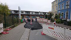 Blick auf eine Baustelle mit fahrenden Autos und einer Radfahrerin