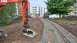 Baustelle mit Bagger und angelegtem Weg zwischen Wohngebäuden