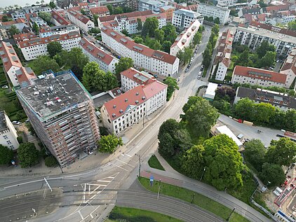 Luftaufnahme einer Kreuzung mit mehreren Straßen, umgeben von Gebäuden und Bäumen.