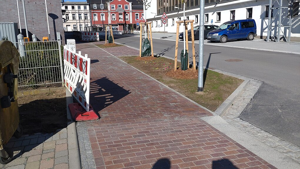 Bürgersteig mit Gebäuden und geparkten Autos.