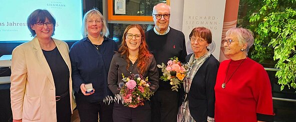 Gruppe von Person stehen nebeneinander und lächeln für ein Foto.