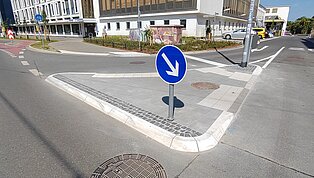 Straßenkreuzung mit Pfeilschild.