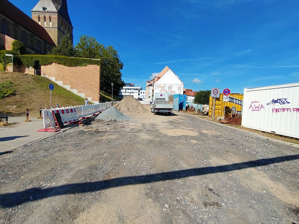 Blick auf eine kaputte Straße mit Fahrzeug im Hintergund.