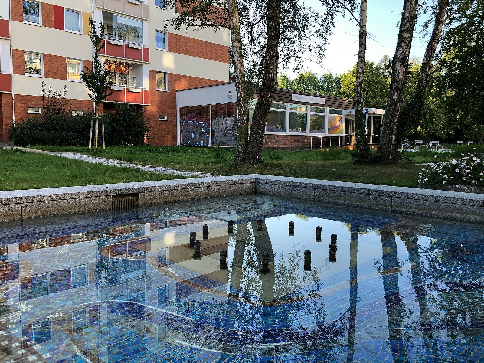 Ein Brunnen umgeben von Grünflächen und Häusern.