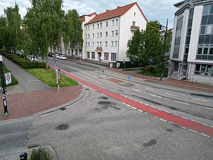 Straße mit Radweg, Gehweg und mehrstöckigen Gebäuden im Hintergrund