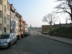 Blick auf eine Straße hinuter mit parkenden Autos an der Seite.