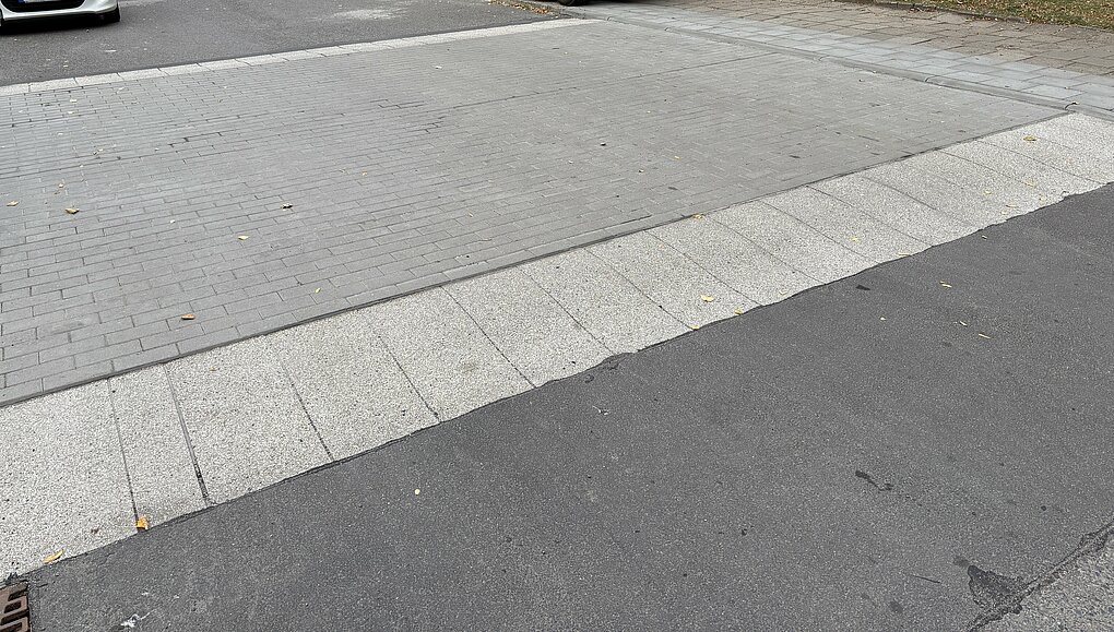 Blick auf eine Straße mit parkenden Autos im Hintergund.