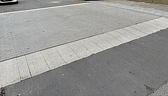 Blick auf eine Straße mit parkenden Autos im Hintergund.