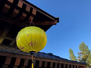 Ein gelber Lampion hängend an einem Dach.