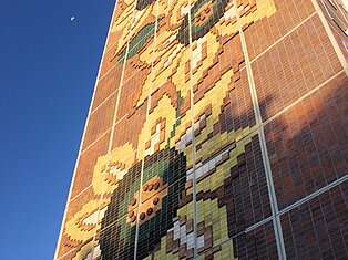 Hauswand mit Sonnenblumenkacheln.