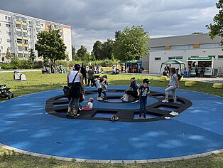 Kinder spielen auf einem runden blauen Trampolin.